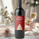 Tree snow red white Christmas Wine Label<br><div class="desc">A red background and white text.  Decorated with a snowcovered pine tree. Merry Christmas is written with an elegant hand-lettered style script.  Personalise and add your family name and year.</div>