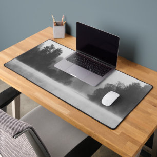 Trees disappearing in morning fog above the lake desk mat