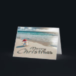Tropical Christmas Snowman On a Beach Holiday Card<br><div class="desc">A small sand snowman wearing a Santa hat stands on a sandy beach with "Merry Christmas" written in the sand</div>