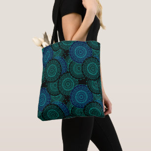 Turquoise blue round mandala on black background tote bag