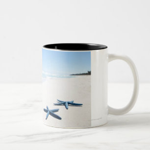 Two blue starfish at water's edge on tropical 2 Two-Tone coffee mug