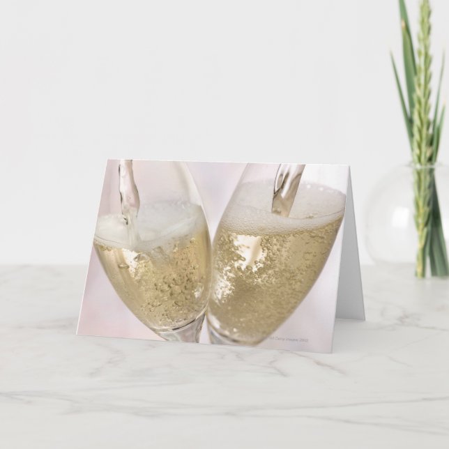 Two champagne flutes being filled with sparkling card (Front)