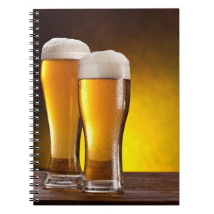 Two glasses of beers on a wooden table spiral notebook