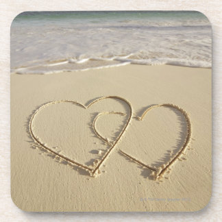 Two overlying hearts drawn on the beach with coaster
