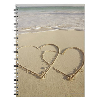 Two overlying hearts drawn on the beach with notebook