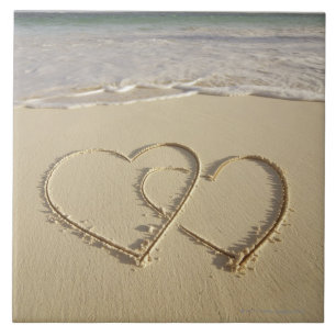 Two overlying hearts drawn on the beach with tile