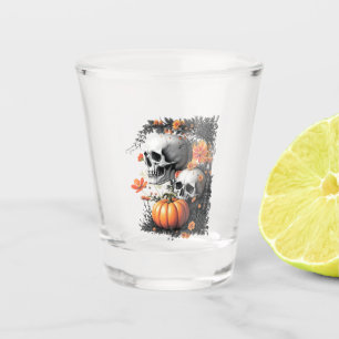 Two skulls and a pumpkin among flowers. shot glass