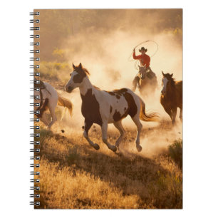 Two western cowboys riding horses, roping wild hor notebook