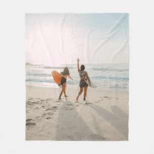 Two women walking towards the ocean carrying surfb fleece blanket