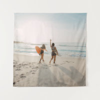 Two women walking towards the ocean carrying surfb