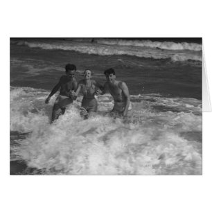 Two young men and woman playing in wave B&W