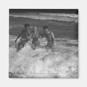 Two young men and woman playing in wave B&W Magnet