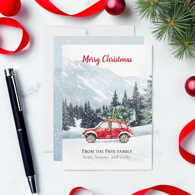 Watercolor Red Car Christmas Tree Holiday Card (Christmas holiday red car with Christmas tree on a snowy mountain top. Card is on marble countertop)