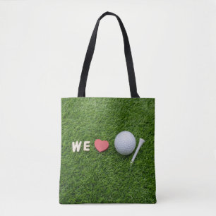 We love golf with golf ball and tee on green grass tote bag
