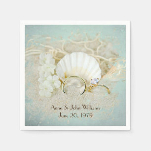 wedding rings and seashells in sand napkin