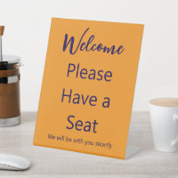 Welcome Please Have a Seat Orange and Blue Text