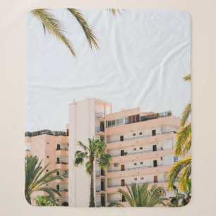 WHITE CONCRETE BUILDING BESIDE GREEN PALM TREE UND SHERPA BLANKET