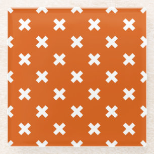 White cross stitches on burnt orange glass coaster