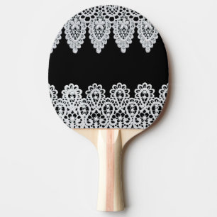 White lace forms a delicate border against black ping pong paddle