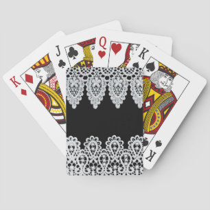 White lace forms a delicate border against black playing cards