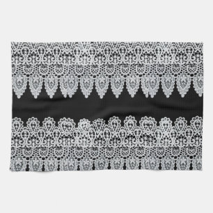 White lace forms a delicate border against black tea towel