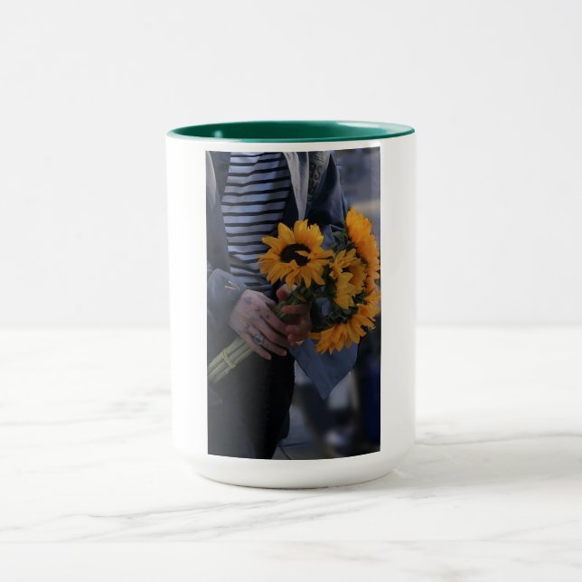 White mug where a hand hold sunflowers with AJ (Center)
