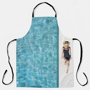 Woman in black bikini bottom and white sun hat sta apron