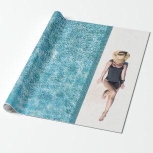 Woman in black bikini bottom and white sun hat sta wrapping paper