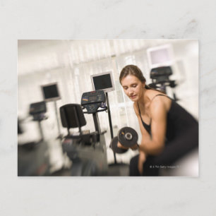 Woman lifting weights in gym 2 postcard