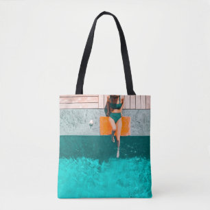 Woman lying beside swimming pool in the morning tote bag