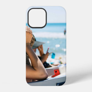 Woman lying on sun lounger covering her face with iPhone 12 case