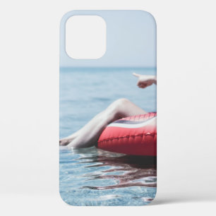 Woman on an inflatable float in the ocean pointing iPhone 12 case