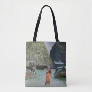 Woman on body of water between brown boats tote bag