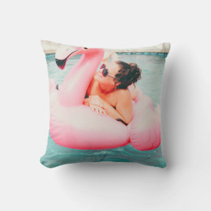 Woman on pink inflatable flamingo on outdoor pool cushion
