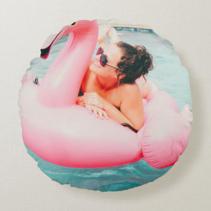 Woman on pink inflatable flamingo on outdoor pool round cushion