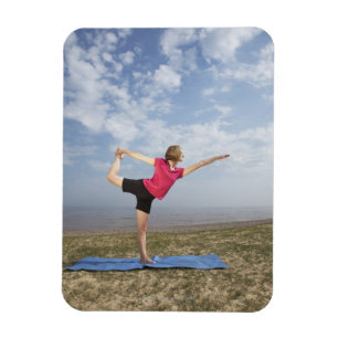 Woman practicing yoga by the beach magnet