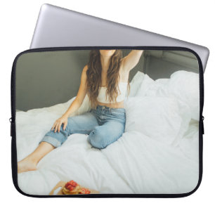 Woman sitting on bed holding her hat laptop sleeve