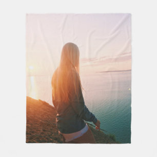 Woman stands near body of water during golden hour fleece blanket
