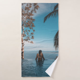 Woman wearing black bikini tap swimming on body of bath towel