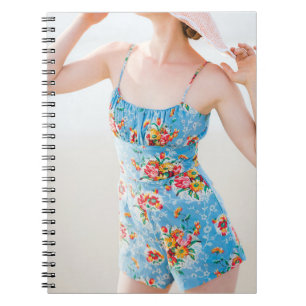 Woman wearing blue floral rompers and brown hat notebook