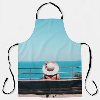 Woman wearing white straw hat sitting on bench loo apron
