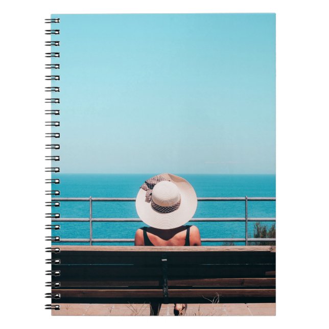 Woman wearing white straw hat sitting on bench loo notebook (Front)