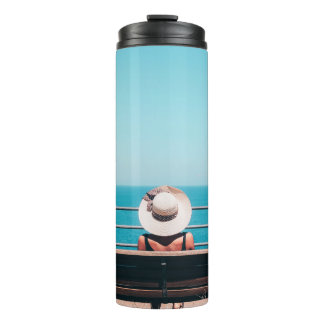 Woman wearing white straw hat sitting on bench loo thermal tumbler