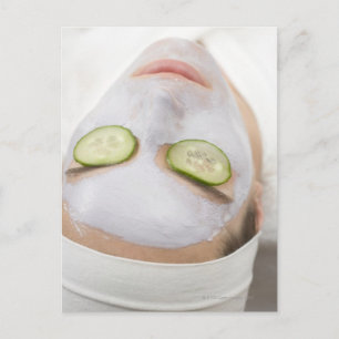Woman with face mask and cucumber slices on postcard