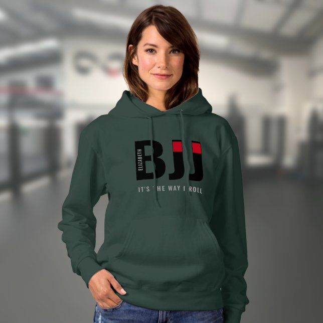 Woman's BJJ Personalised Hoodie (Dark green woman's BJJ hoodie worn by a female model in a gym.)