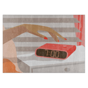 Womans hand pushing on alarm clock snooze button cutting board