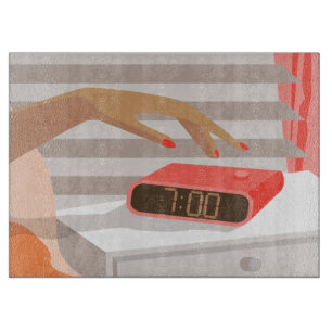 Womans hand pushing on alarm clock snooze button cutting board