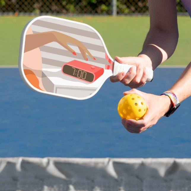 Womans hand pushing on alarm clock snooze button pickleball paddle (Insitu)