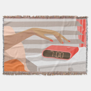 Womans hand pushing on alarm clock snooze button throw blanket