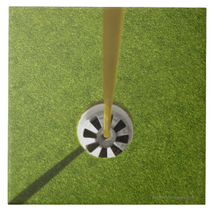 Yellow golf flag pole and hole tile